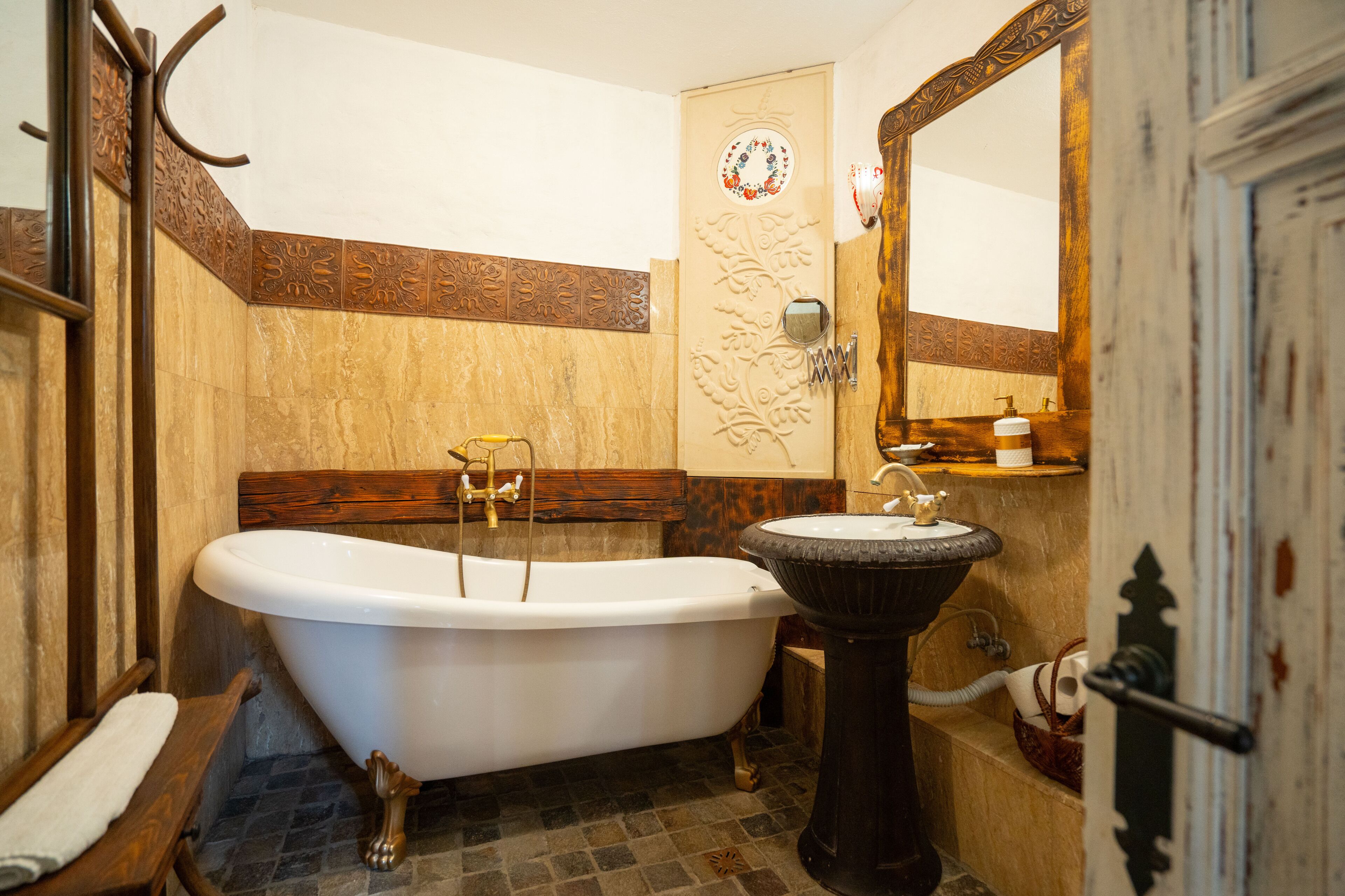 A bathroom with a clawfoot bathtub, a pedestal sink, and a wooden vanity.