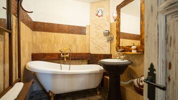 A bathroom with a clawfoot bathtub, a pedestal sink, and a wooden vanity.
