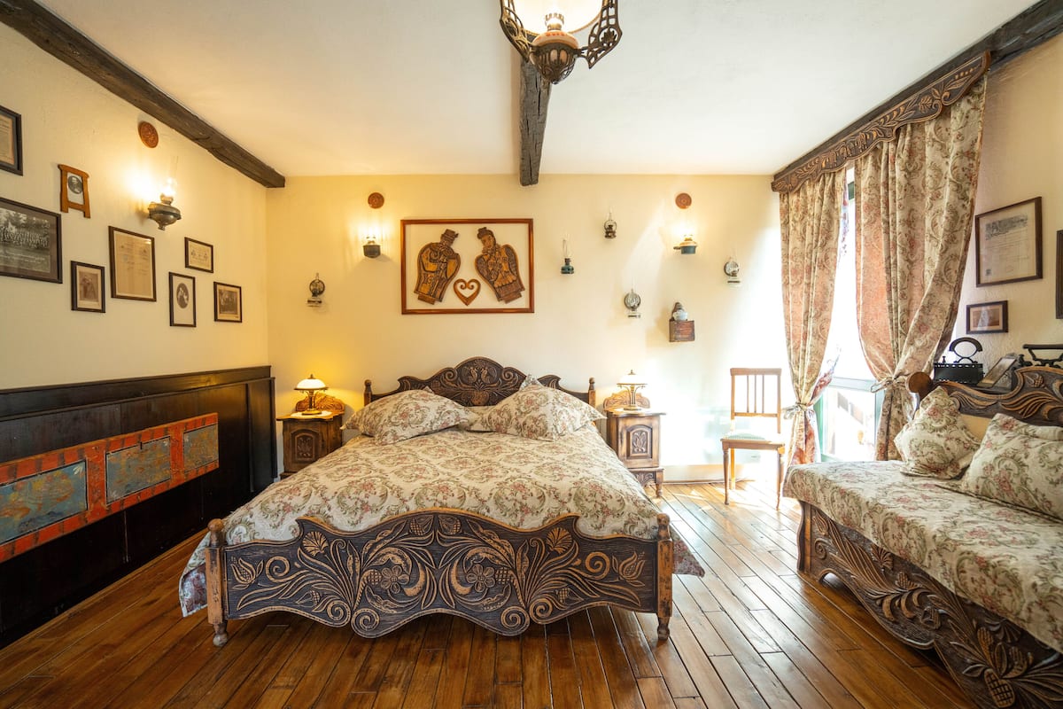 A traditional room with a wooden bed, a sofa, and a wooden floor.