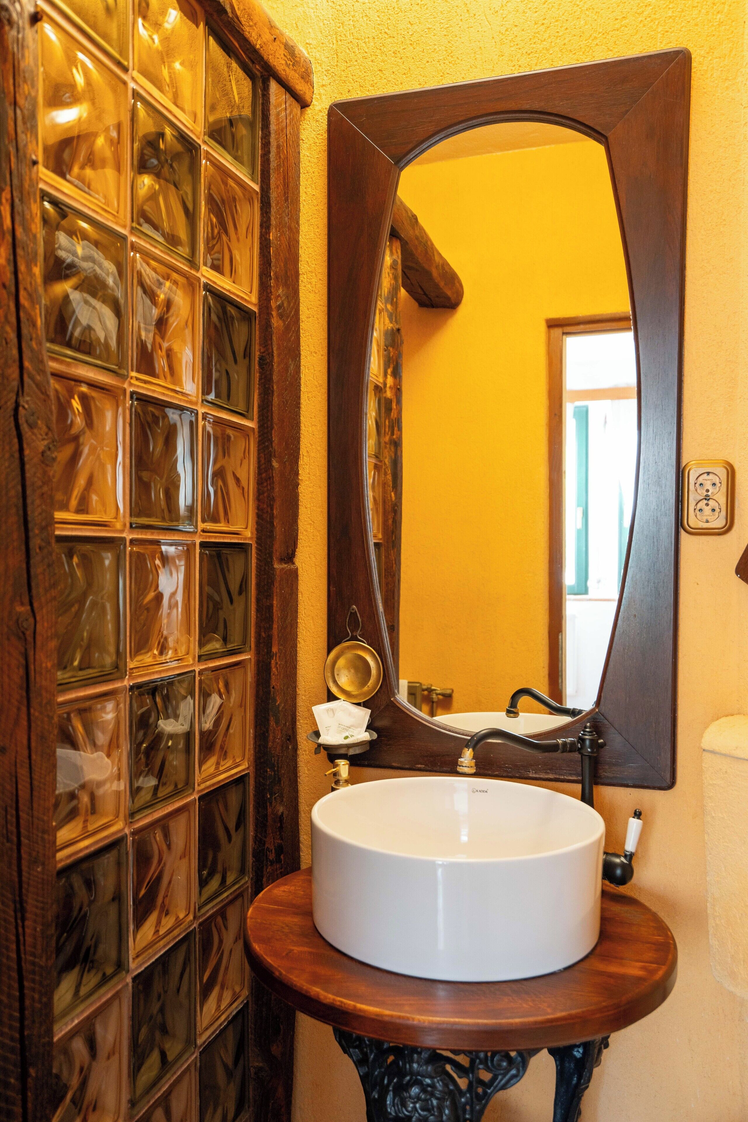 A bathroom with a wooden vanity, a white sink, and a mirror.