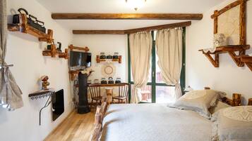 Una habitación acogedora con cama, vigas de madera, televisor y una mesita con sillas.