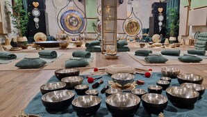 Una habitación con varias zonas de meditación, cada una con un tapete, cojines y una variedad de cuencos y cascabeles.