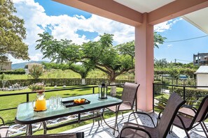 A covered outdoor seating area with a table, chairs, and a pitcher of orange juice. - Apartment 'House Of Dreams Lefkada' with Sea View, Wi-Fi and Air Conditioning (LEFKADA)