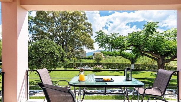 Une terrasse extérieure avec une table et des chaises, une carafe de jus d’orange et un plateau rempli d’oranges.