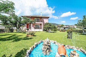 A two-story building with a swimming pool, surrounded by a well-maintained lawn and trees.