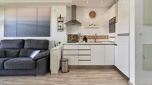 Una cocina moderna con armarios blancos, horno empotrado y una isla grande con fregadero.