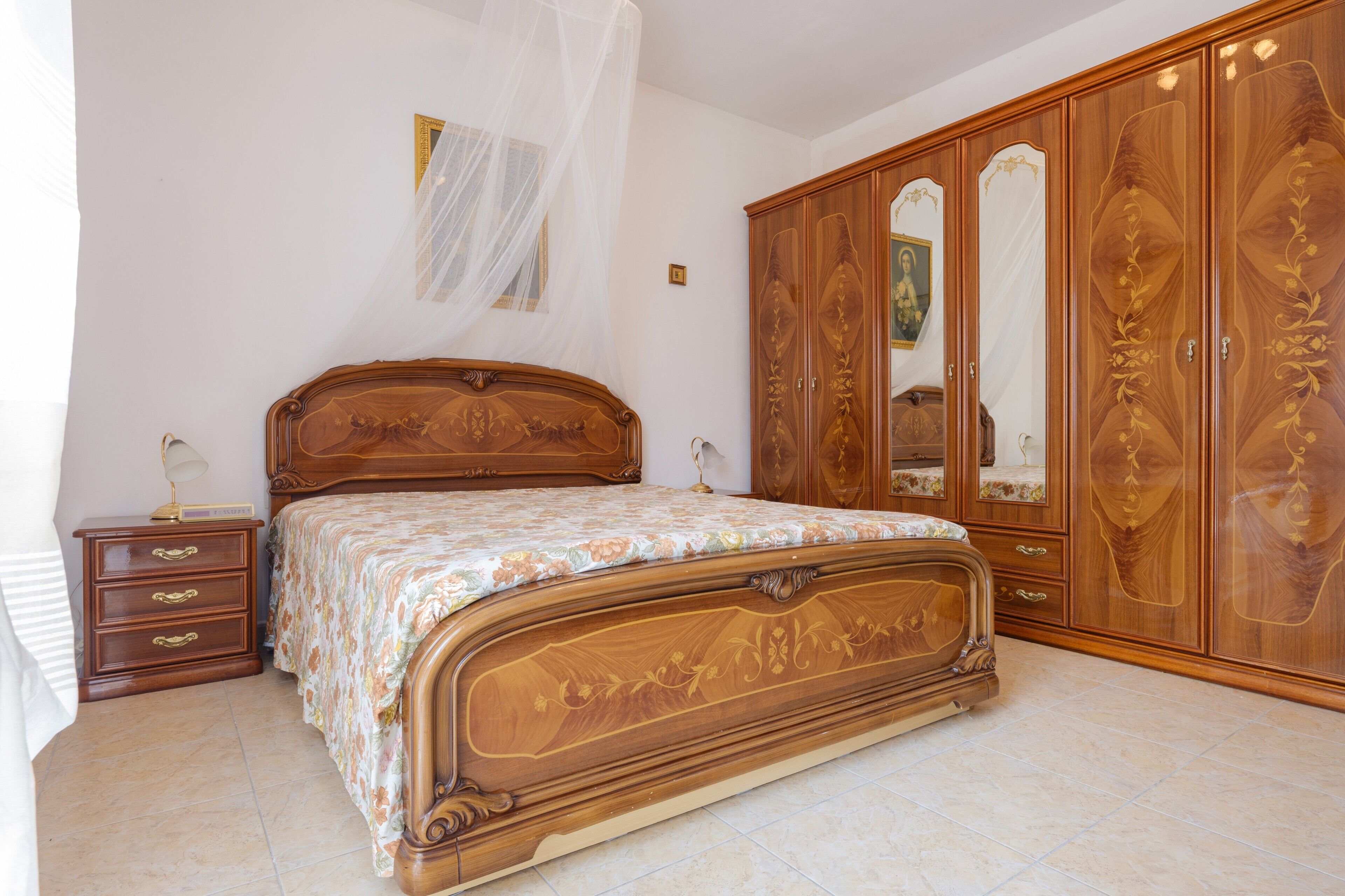 Un dormitorio con cama de madera, mesita de noche, armario y dosel.