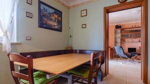 Un'area pranzo con un tavolo e sedie in legno, un quadro appeso al muro e una libreria sullo sfondo.