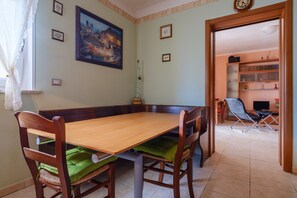 Un coin repas avec une table et des chaises en bois, un tableau au mur et une bibliothèque en arrière-plan.