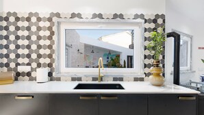 Une cuisine au design moderne, dotée d’une grande fenêtre, d’un évier et d’une plante décorative.