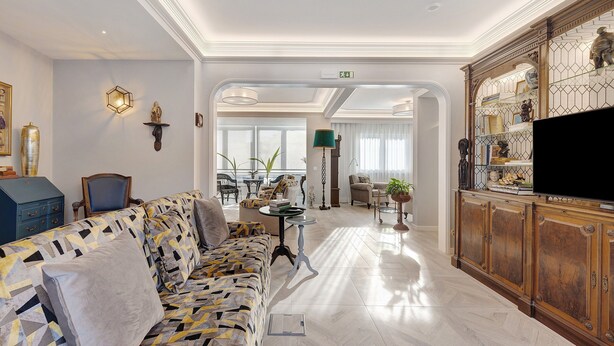 Un salon moderne avec un canapé à motifs, un téléviseur et un meuble en bois.