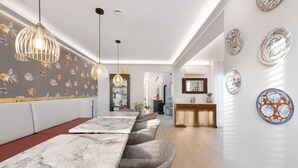 Un espace repas avec des tables en marbre, des chaises en osier, des luminaires suspendus et des assiettes décoratives accrochées au mur.