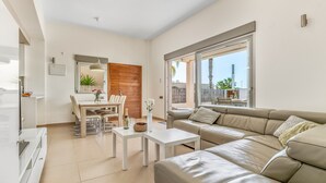 A modern living room with a sofa, dining table, and a view of the outdoors. - Villa "Casa Imjo Groundfloor" with Private Pool, Private Terraces & Air Conditioning (Orihuela Costa)
