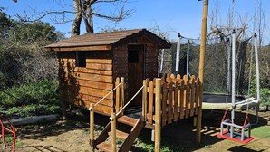 Una casita de juegos de madera con rampa y un columpio.