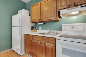 Una cocina con armarios de madera, un refrigerador blanco, un fregadero y una estufa.