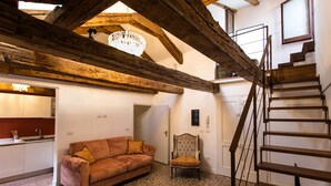 Une pièce chaleureuse avec un plafond en bois, un canapé, un fauteuil et un escalier.