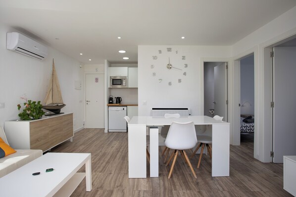 A modern kitchen with white cabinetry, a microwave, and a built-in clock.