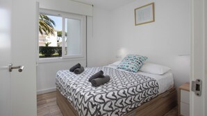 A bedroom with a bed, a window, a door, and a nightstand. - Apartment with pool and parking. Ground floor with garden (Palafrugell)