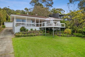 A modern two-story house with a covered patio, a driveway, and a well-maintained garden.