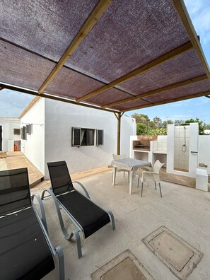 A covered outdoor area with a table and chairs, a small pool, and a white building with windows and a door. - Apartment for 2–3 people with a garden, parking, air conditioning, and Wi-Fi. C/DISCOUNTS FOR JULY–SEPTEMBER (San Fernando)