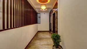A hallway with a chandelier, a potted plant, and a door with a security keypad. - Treebo Three Street Inn (Bengaluru)