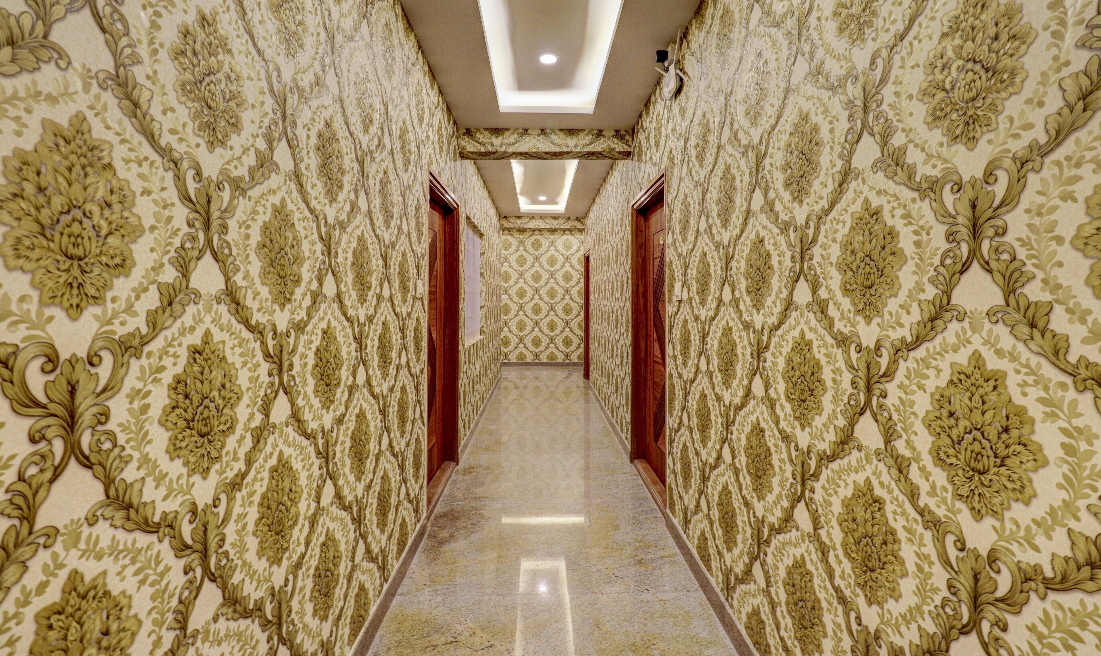 A hallway with ornate wallpaper and a reflective floor.