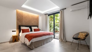 A modern bedroom with a skylight, a bed with red and white bedding, a wooden headboard, and a view of greenery outside.