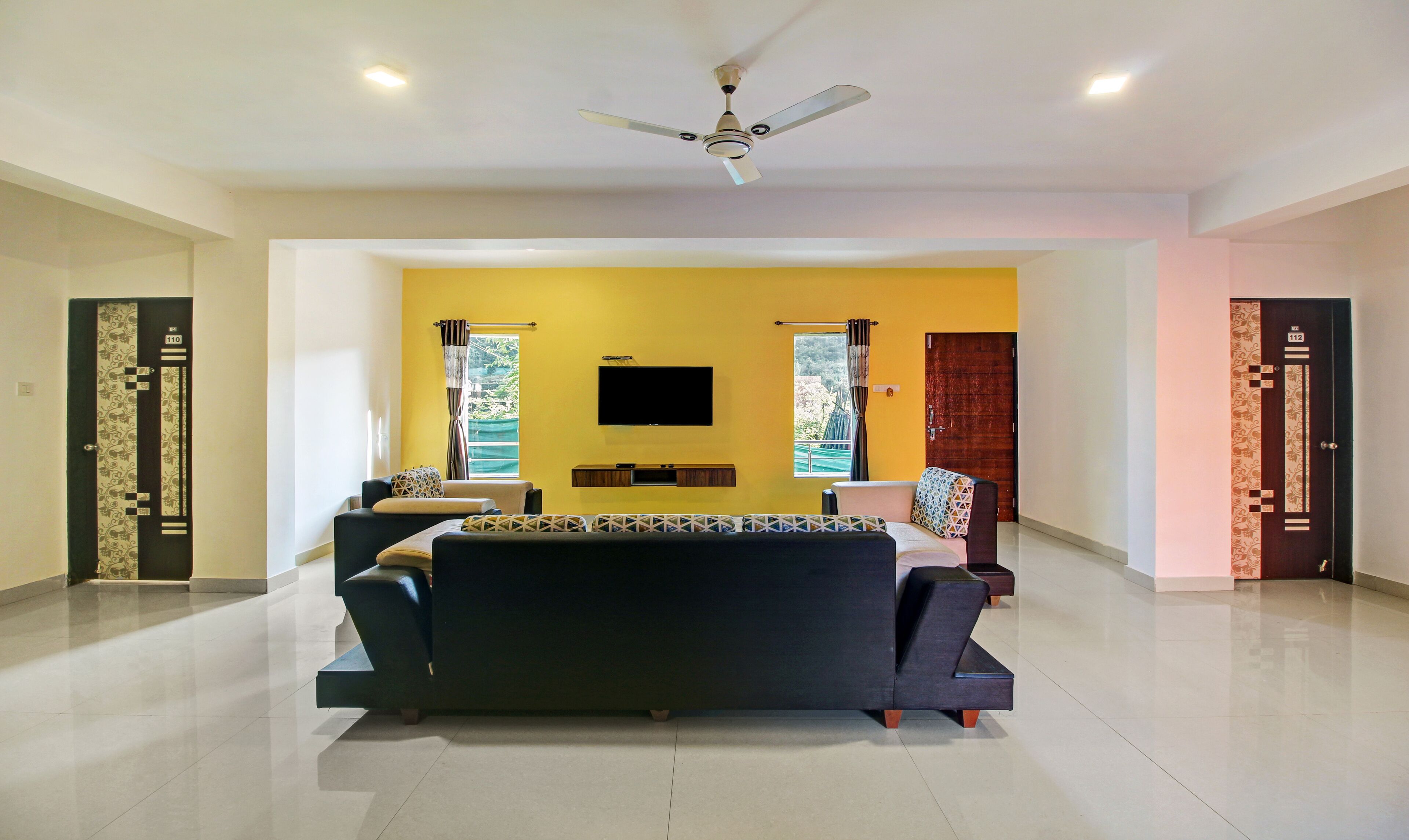 A modern living room with a sofa, TV, and ceiling fan.