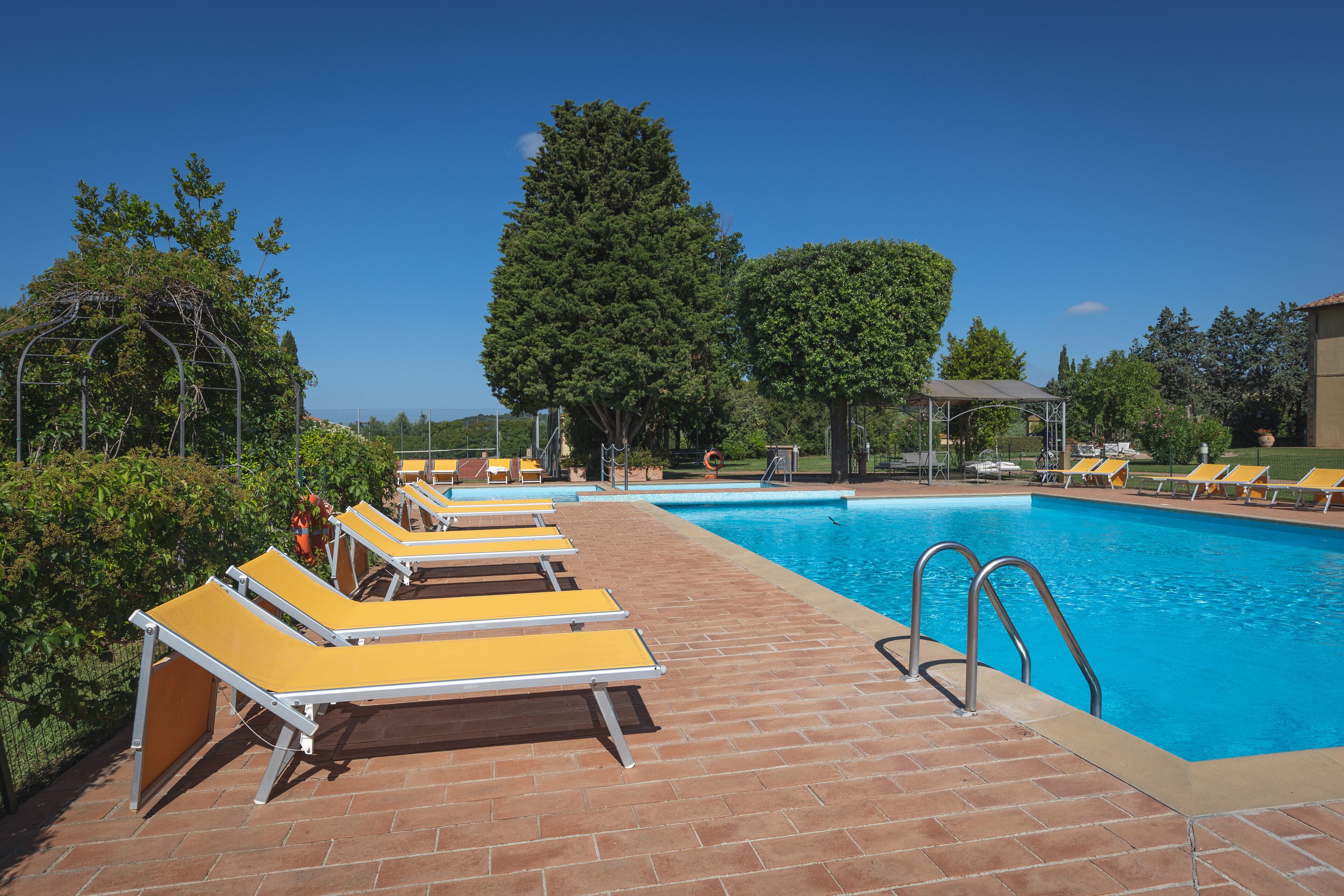 Ein Poolbereich mit Liegestühlen und blauem Himmel.