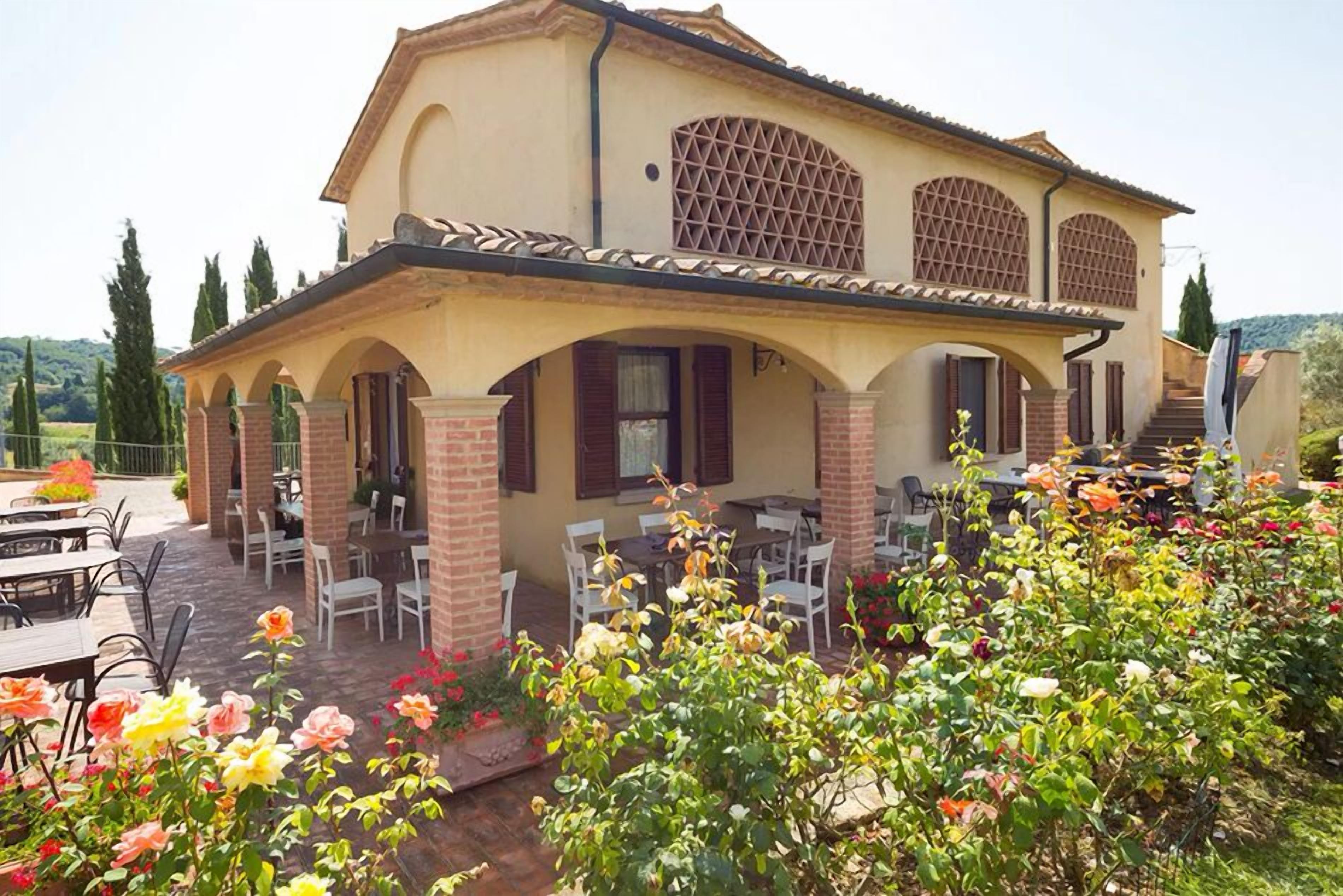 A two-story house with a patio area featuring outdoor seating and a garden with flowering plants.