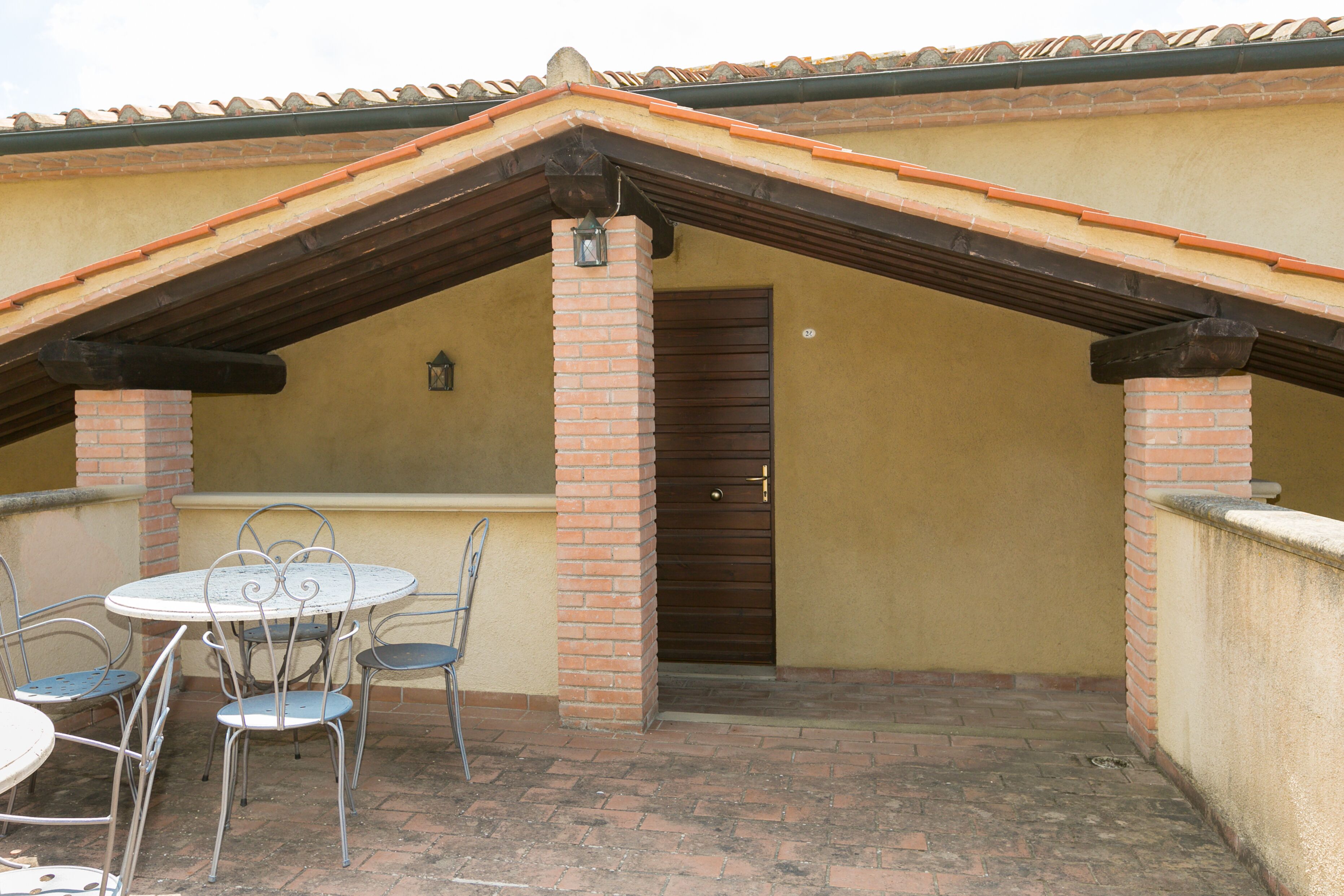 Un patio con pared de ladrillo, una puerta y una mesa con sillas.
