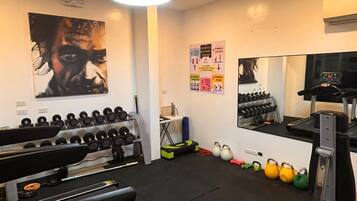 A gym with treadmills, dumbbells, kettlebells, and a mirror.