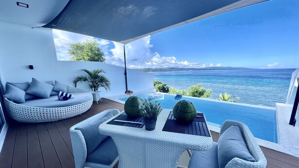 Un espace extérieur moderne avec des sièges et une piscine donnant sur la mer.