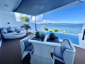 A modern outdoor seating area with a pool overlooking the sea. - Epic Suites Bohol - Adults Only (Dauis)