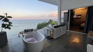 Une salle de bain moderne avec une grande baignoire, une plante en pot et une vue sur la mer.