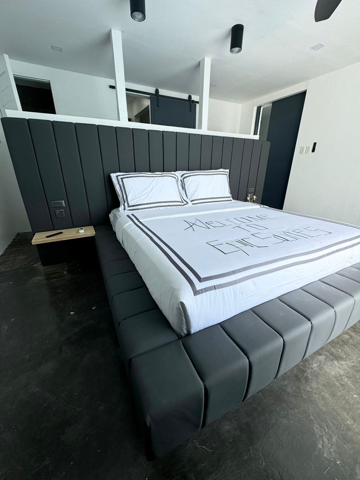 A modern bedroom with a large bed, a bedside table, and a built-in bench.