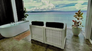 Une salle de bain avec une baignoire, une grande fenêtre et une vue sur la mer.