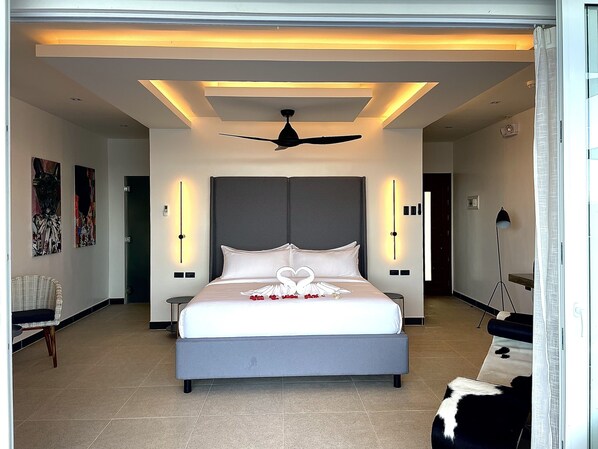 A modern hotel room with a large bed, a ceiling fan, and wall-mounted lighting. - Epic Suites Bohol - Adults Only (Dauis)