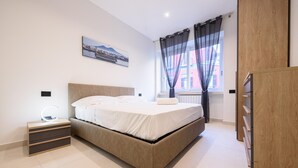 A modern bedroom with a bed, bedside table, and a wardrobe. - Via Niccolo Tommaseo 4 - Appartamento 1 (Naples)