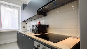 A modern kitchen with dark cabinets, a black microwave, and a wooden countertop. - Via Niccolo Tommaseo 4 - Appartamento 1 (Naples)