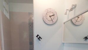A bathroom with a shower, a sink, and two wall clocks. - Quiet semi-detached house with swimming pool (Grasse)