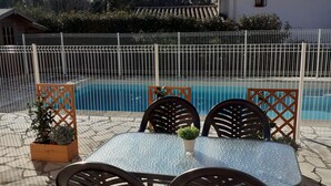 A poolside area with a table and chairs, surrounded by a fence and potted plants. - Quiet semi-detached house with swimming pool (Grasse)