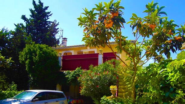A residential area with a parked car, a building with red shutters, and lush greenery. - La Cigale Appart-Villa 60 m² for 2 pers. At Doors of Avignon , in Provence (Vedène)