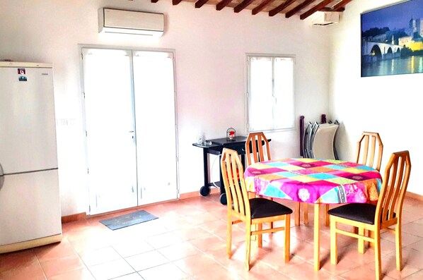 A kitchen with a refrigerator, a table with chairs, a window, and a painting on the wall.