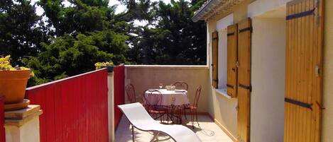 Un pequeño patio al aire libre con una mesa, sillas, una valla roja y una puerta de madera.