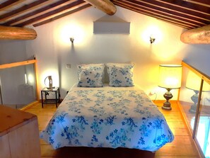 Een slaapkamer met een bed, twee wandlampen, een nachtkastje met een lamp en een plafondventilator.