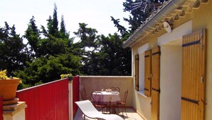 A small outdoor patio with a table and chairs, a red fence, and a wooden door. - La Cigale Appart-Villa 60 m² for 2 pers. At Doors of Avignon , in Provence (Vedène)