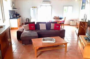 Een woonkamer met een hoekbank, een salontafel en een eethoek met een tafel en stoelen.