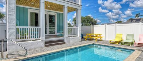 Une maison à deux étages avec une piscine, un patio couvert et une clôture blanche.