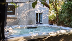 A hot tub in a backyard with a stone wall and a window. - Duplex Le Philandra - 2-4 pers - jacuzzi  (Monteils)